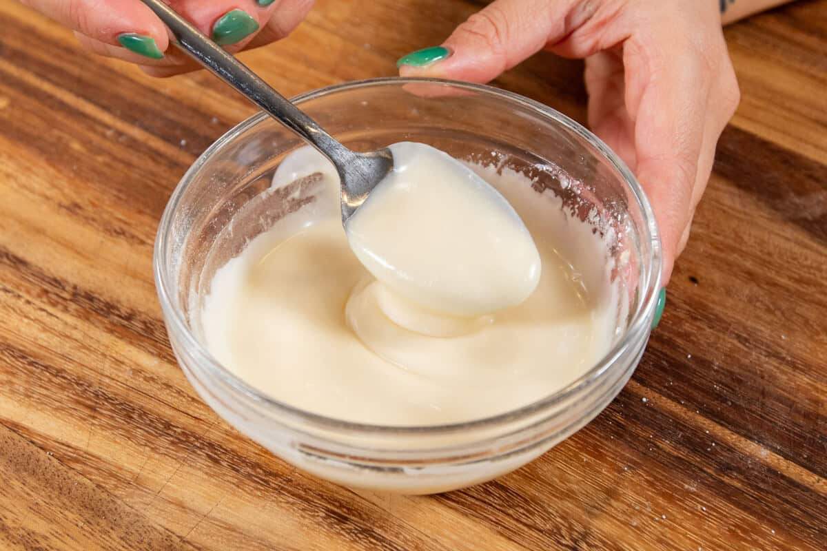 finished cream cheese frosting being scooped with a spoon