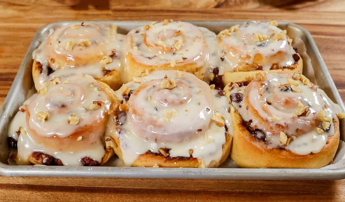 adding chopped walnuts on top of carrot cake cinnamon rolls