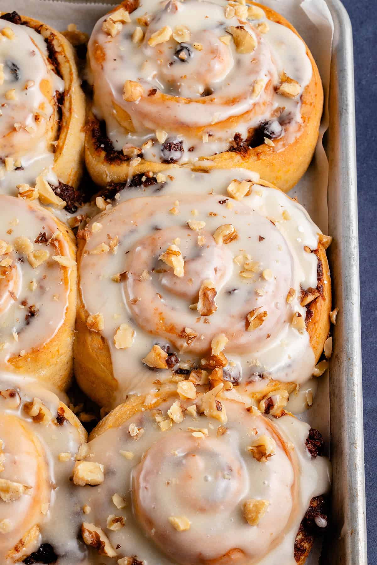 vegan carrot cake cinnamon rolls topped with cream cheese frosting and chopped walnuts