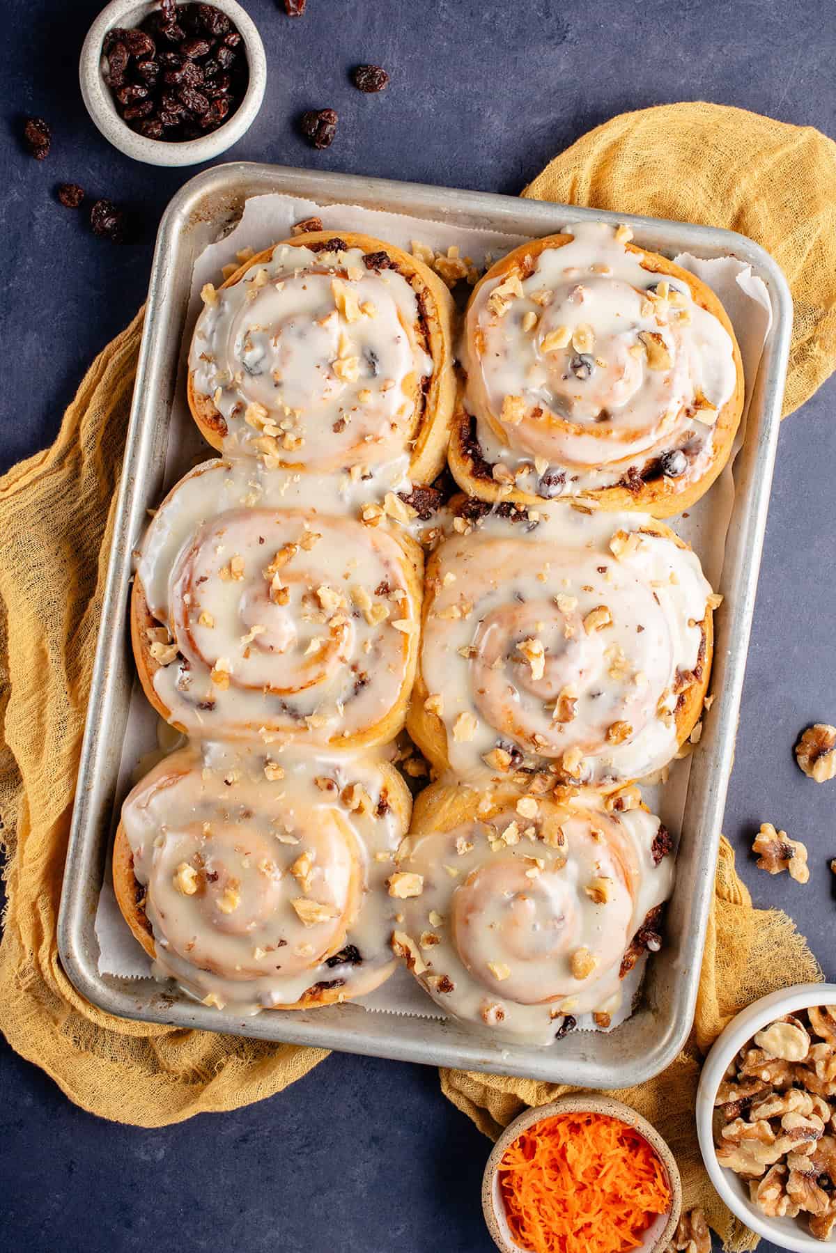 vegan carrot cake cinnamon rolls topped with cream cheese frosting and chopped walnuts