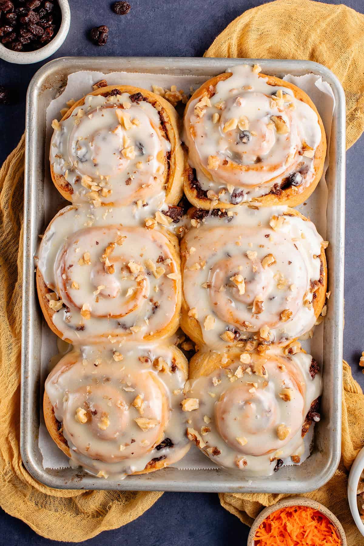 vegan carrot cake cinnamon rolls topped with cream cheese frosting and chopped walnuts