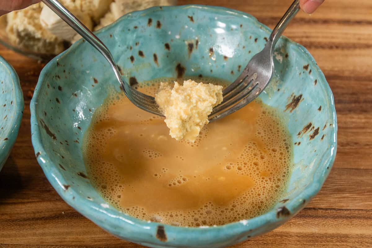 dipping the tofu with two forks into wet batter