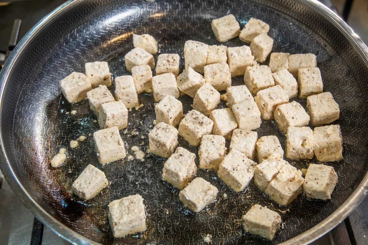 coated tofu frying in a pan