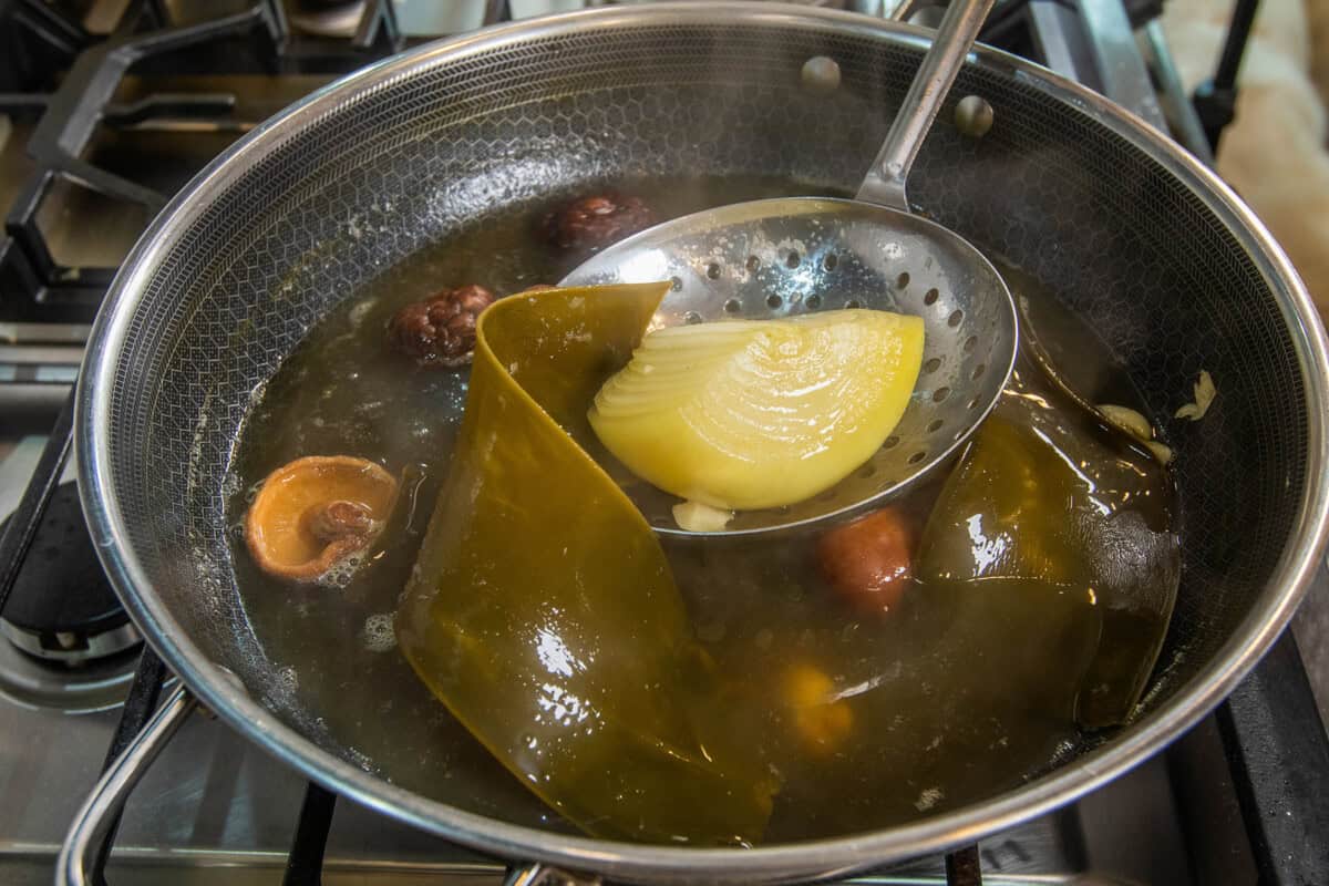 removing onions and vegetables from pot of broth
