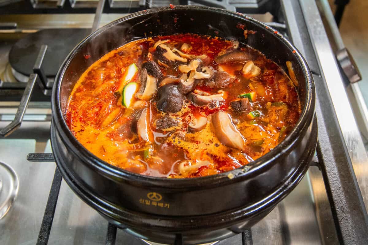 adding mushrooms to stew in pot