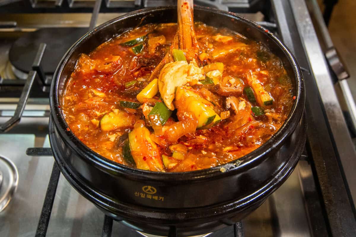 lifting soup out of pot with a wooden spoon