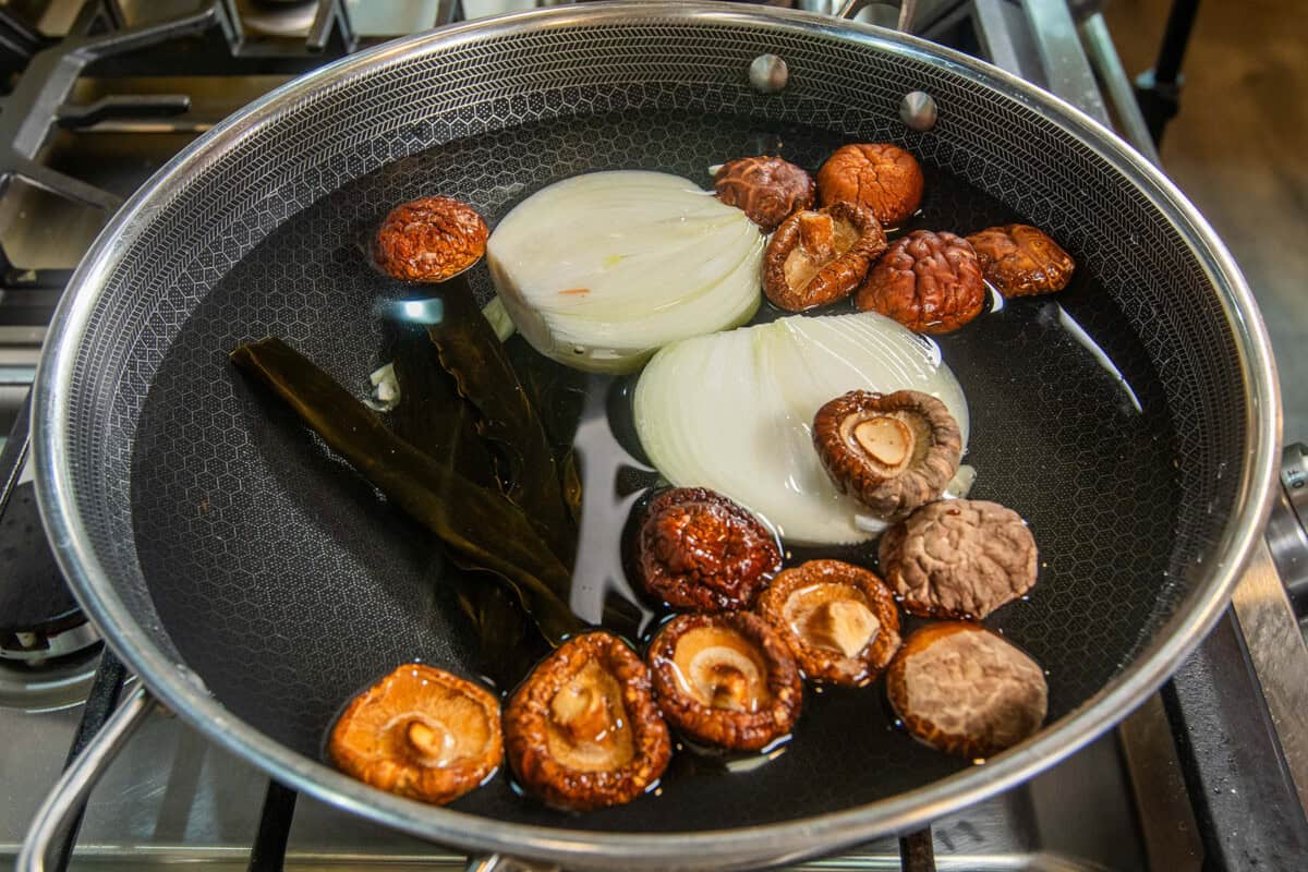 adding mushrooms to pot for broth