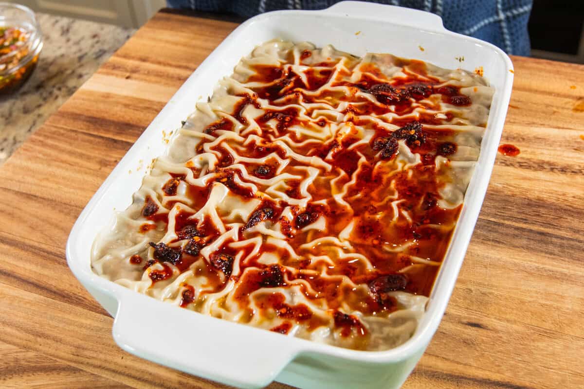 adding chili oil to dumpling lasagna