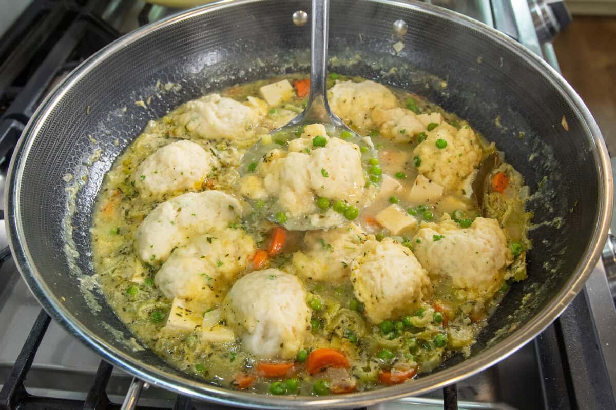 a scoop of tofu and dumplings in pot