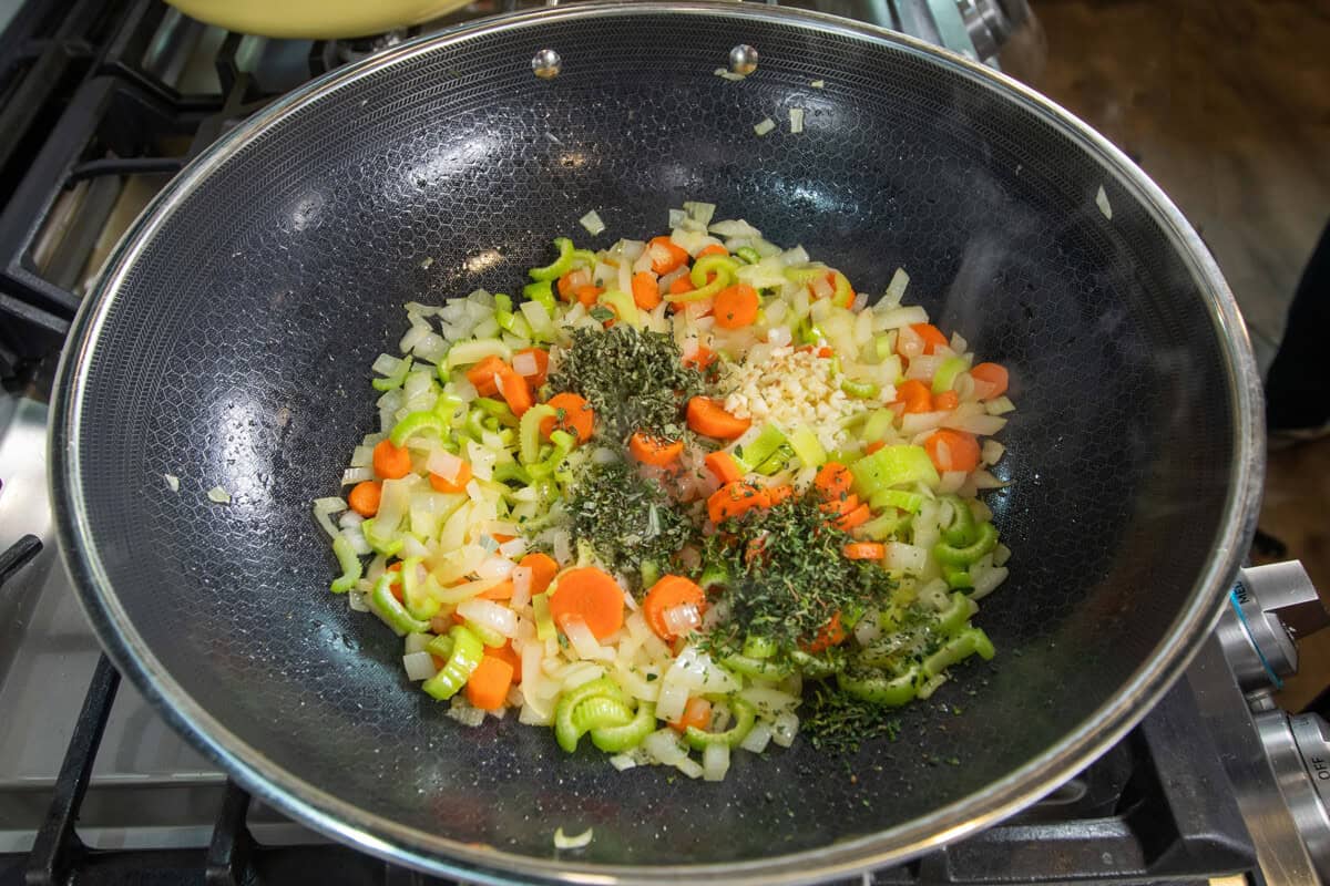 adding garlic and herbs to the pot