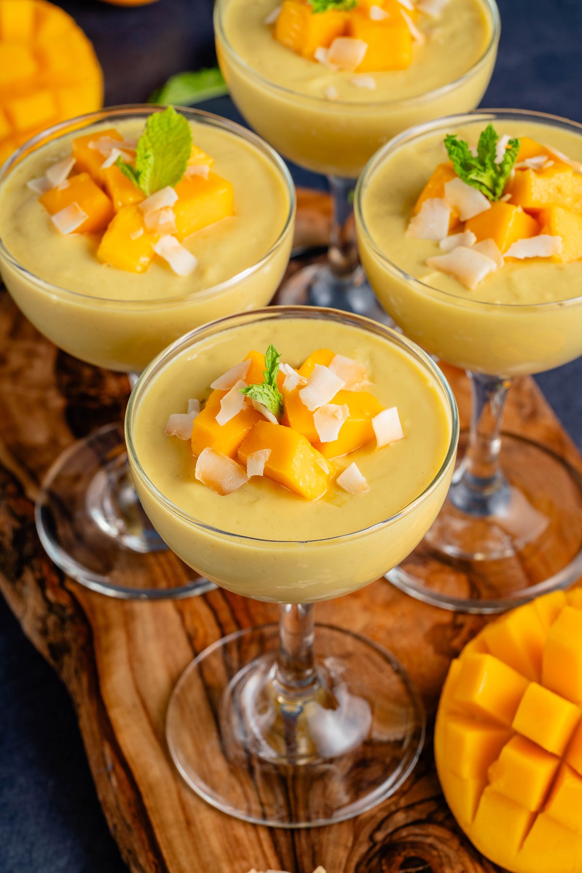 tall glasses of mango posset topped with mango, coconut, and mint