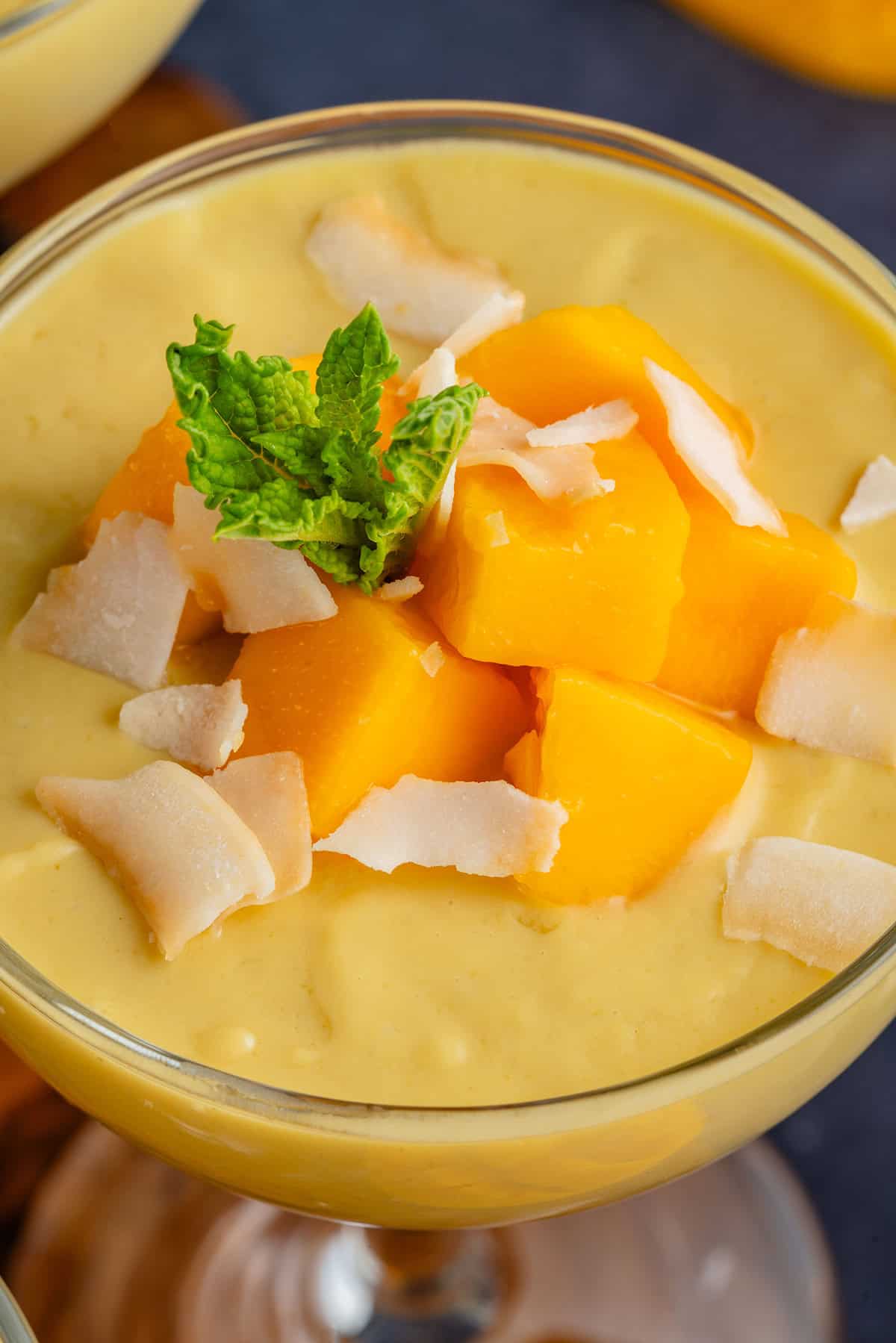 mango posset topped with mango chunks, toasted coconut, and mint