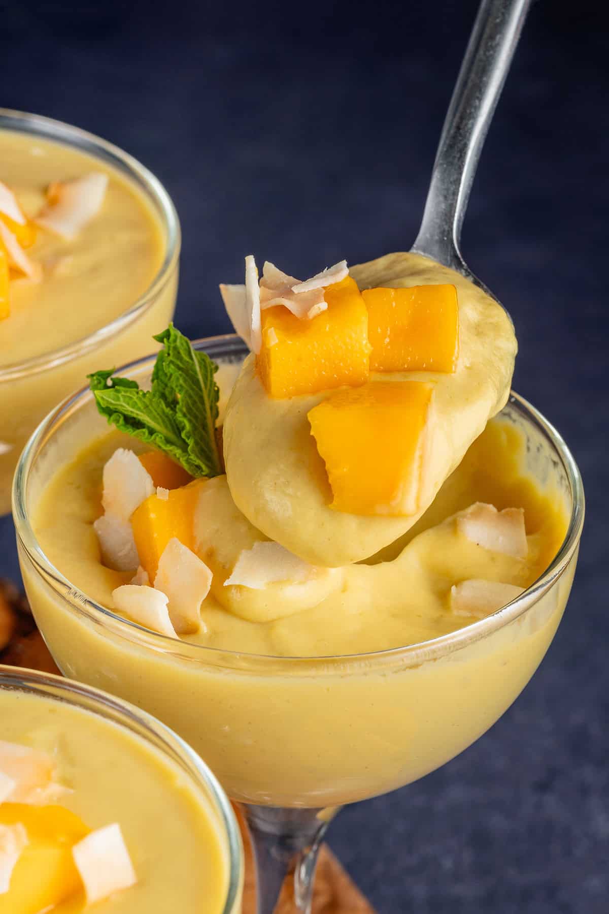 a spoonful of mango posset in a glass