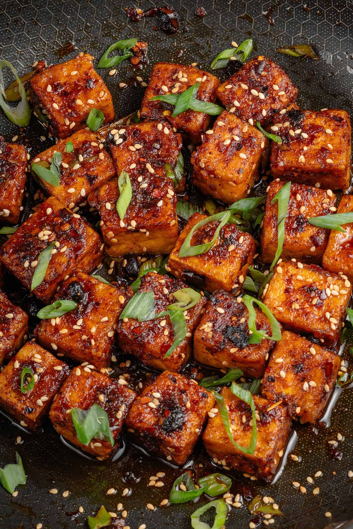 photo of Chili Crisp Tofu cubes in pan with sliced green onions and toasted sesame seeds