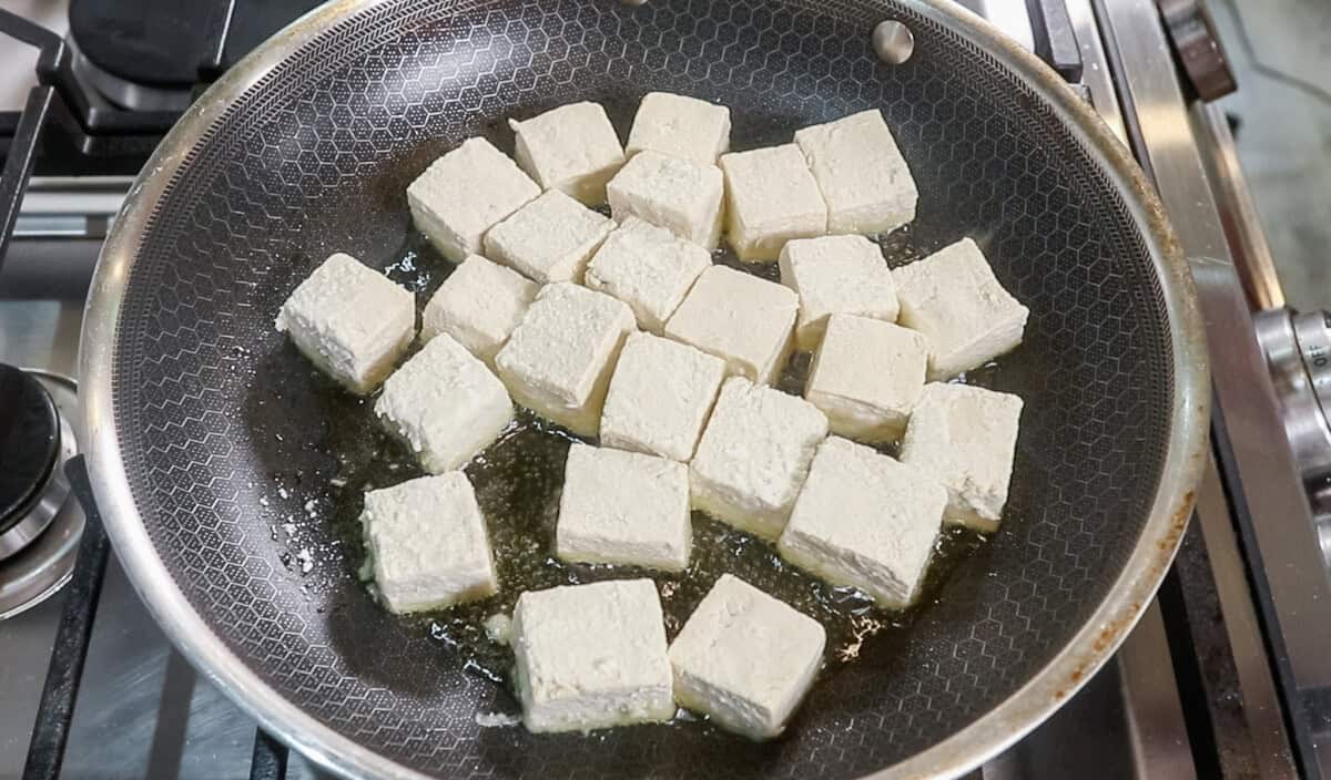 uncooked cornstarch coated tofu pan frying in oil