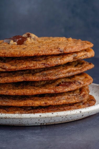 a stack of thin crispy chocolate chip cookies on a plate