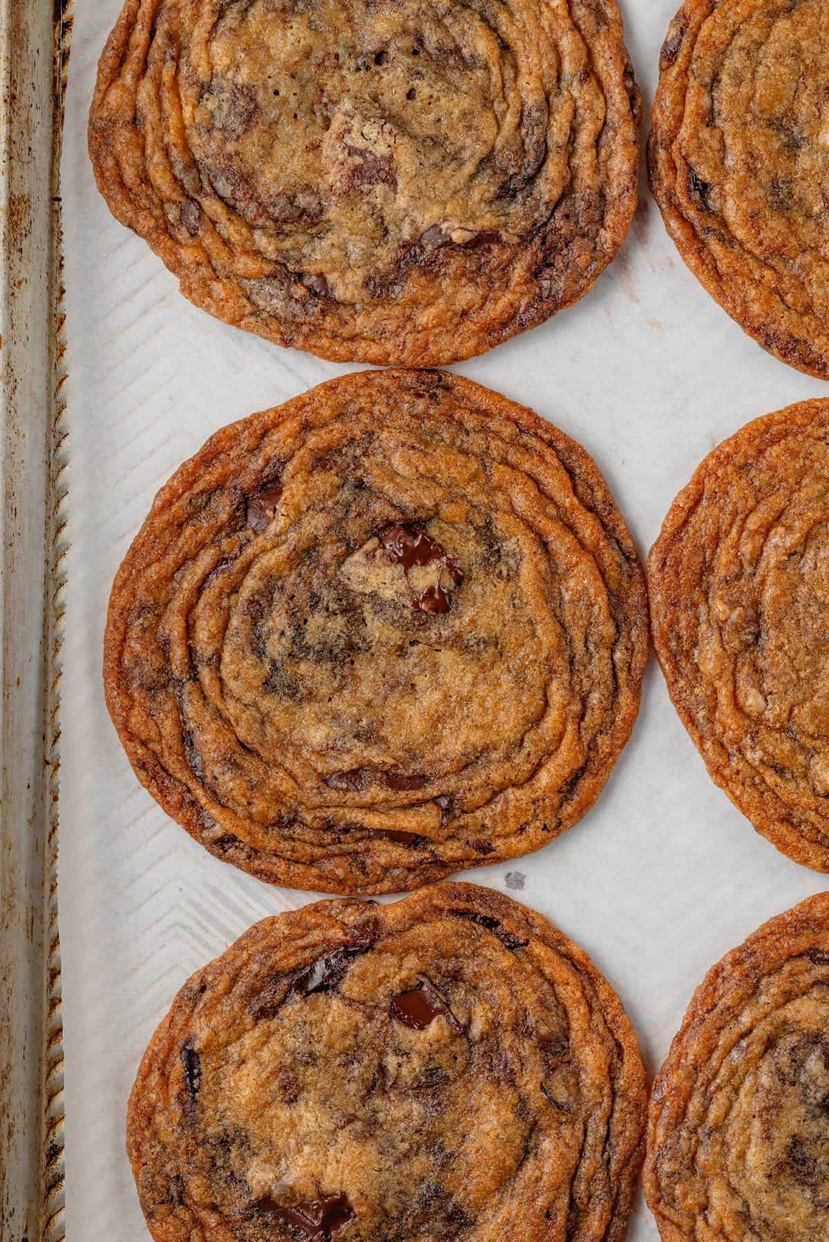 thin crispy chocolate chip cookies on a lined baking sheet
