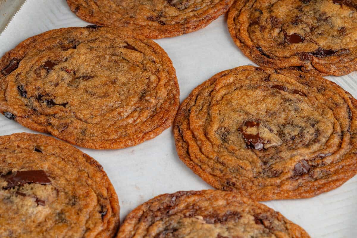 thin crispy chocolate chip cookies on a lined baking sheet