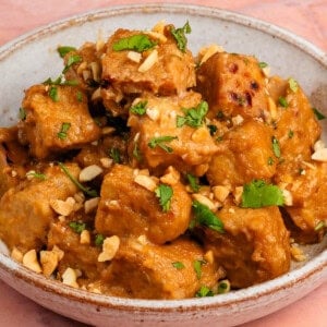 peanut braised tempeh in a bowl topped with cilantro and crushed peanuts