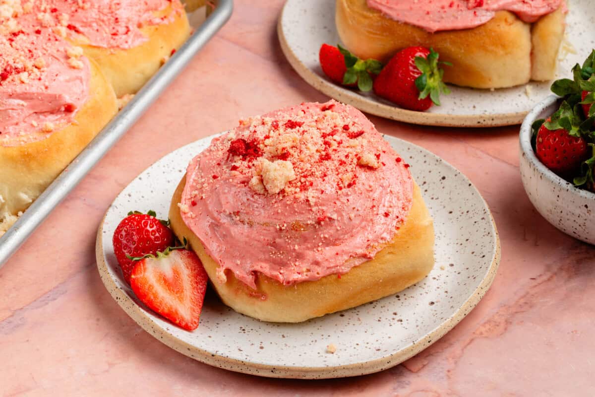 strawberry shortcake sweet rolls on a plate with sheet pan and strawberries in the background