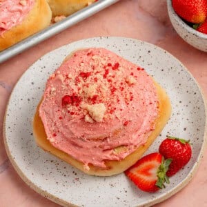 strawberry shortcake sweet rolls on a plate with sheet pan and strawberries in the background