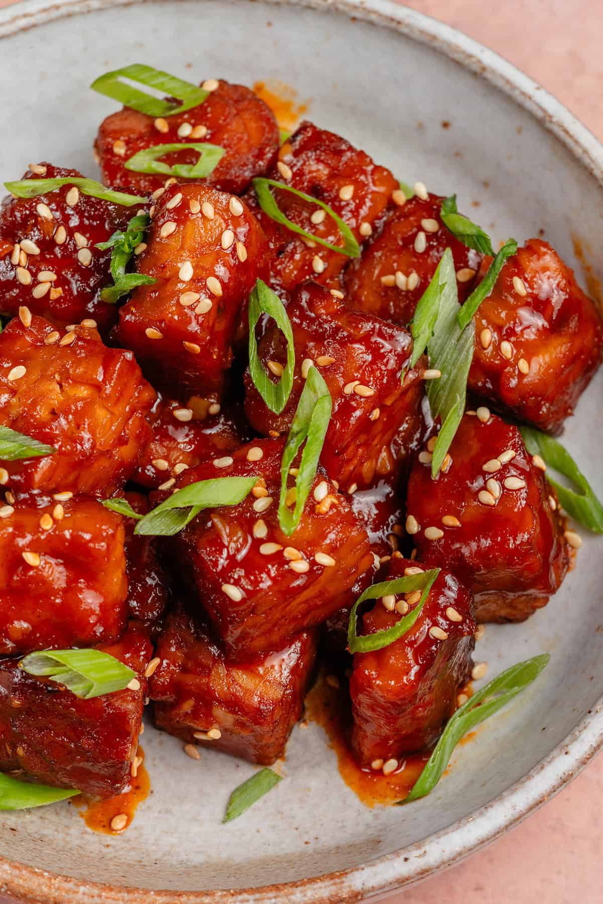 gochujang braised tempeh in a bowl topped with scallions and sesame seeds