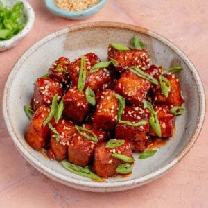 gochujang braised tempeh in a bowl topped with scallions and sesame seeds