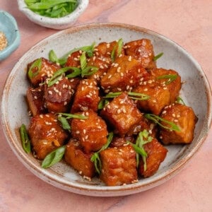 miso maple braised tempeh in a bowl topped with sesame seeds and scallions