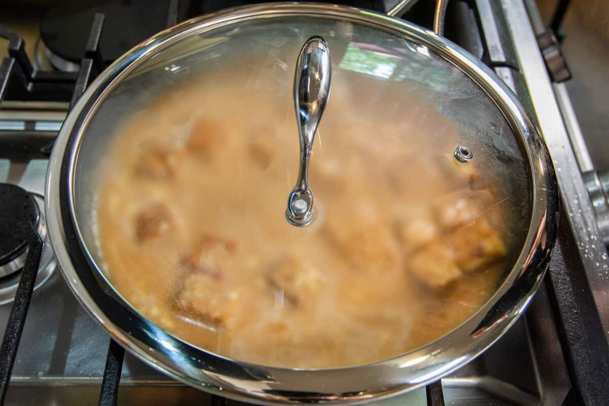 skillet with a lid braising peanut tempeh
