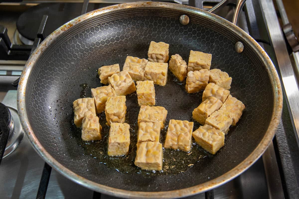 adding tempeh to a skillet with oil