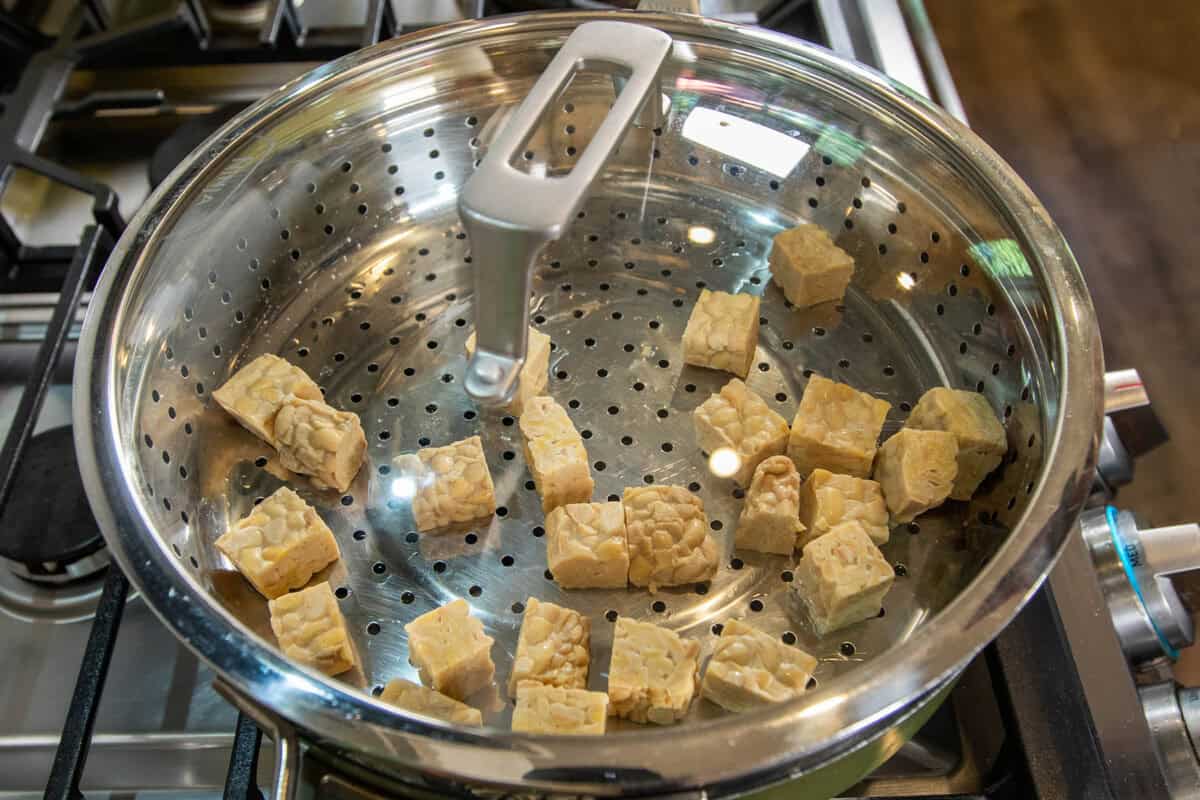 steaming tempeh in a pan with a lid