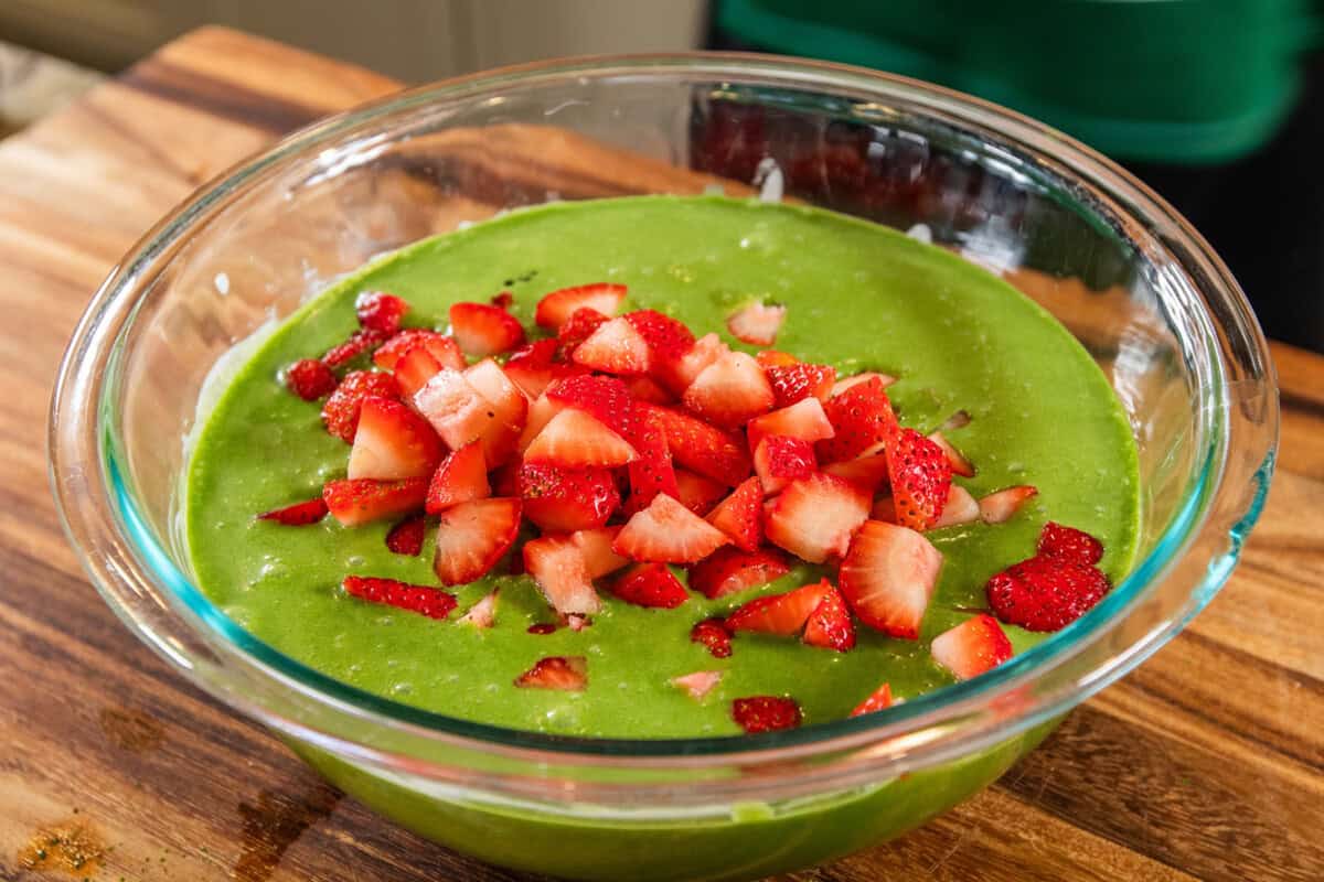 adding fresh sliced strawberries to the bowl