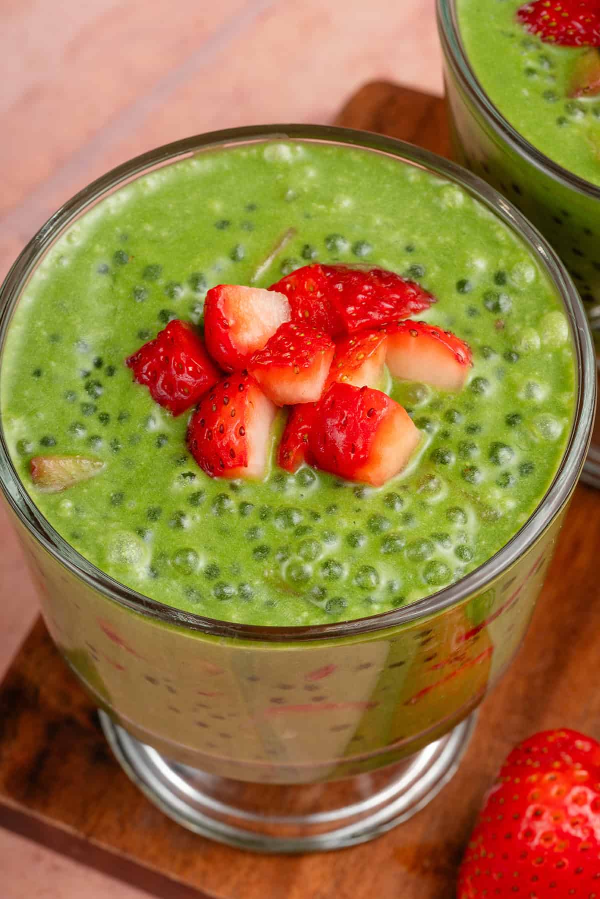 parfait glass filled with strawberry matcha sago and topped with strawberries on wooden board