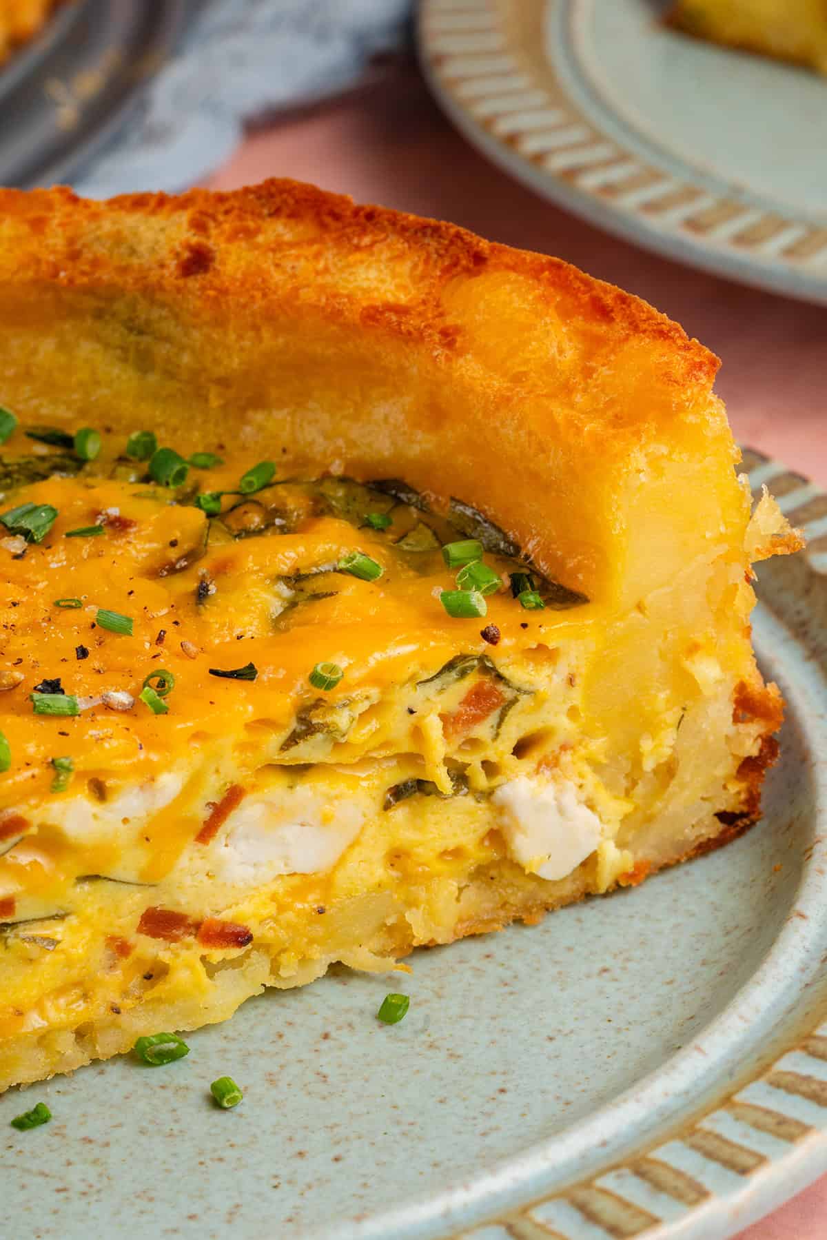 close up of slice of potato crust quiche on a plate