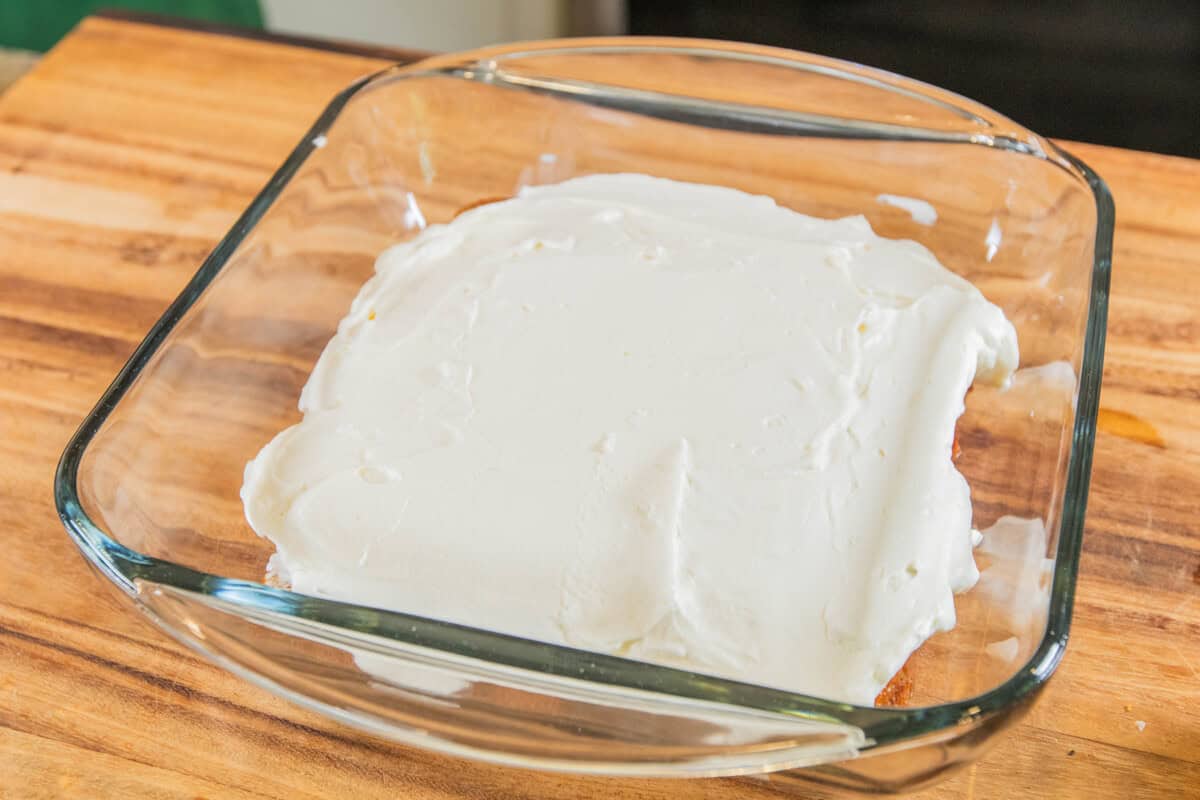 adding a layer of cream on top of soaked banana bread slices