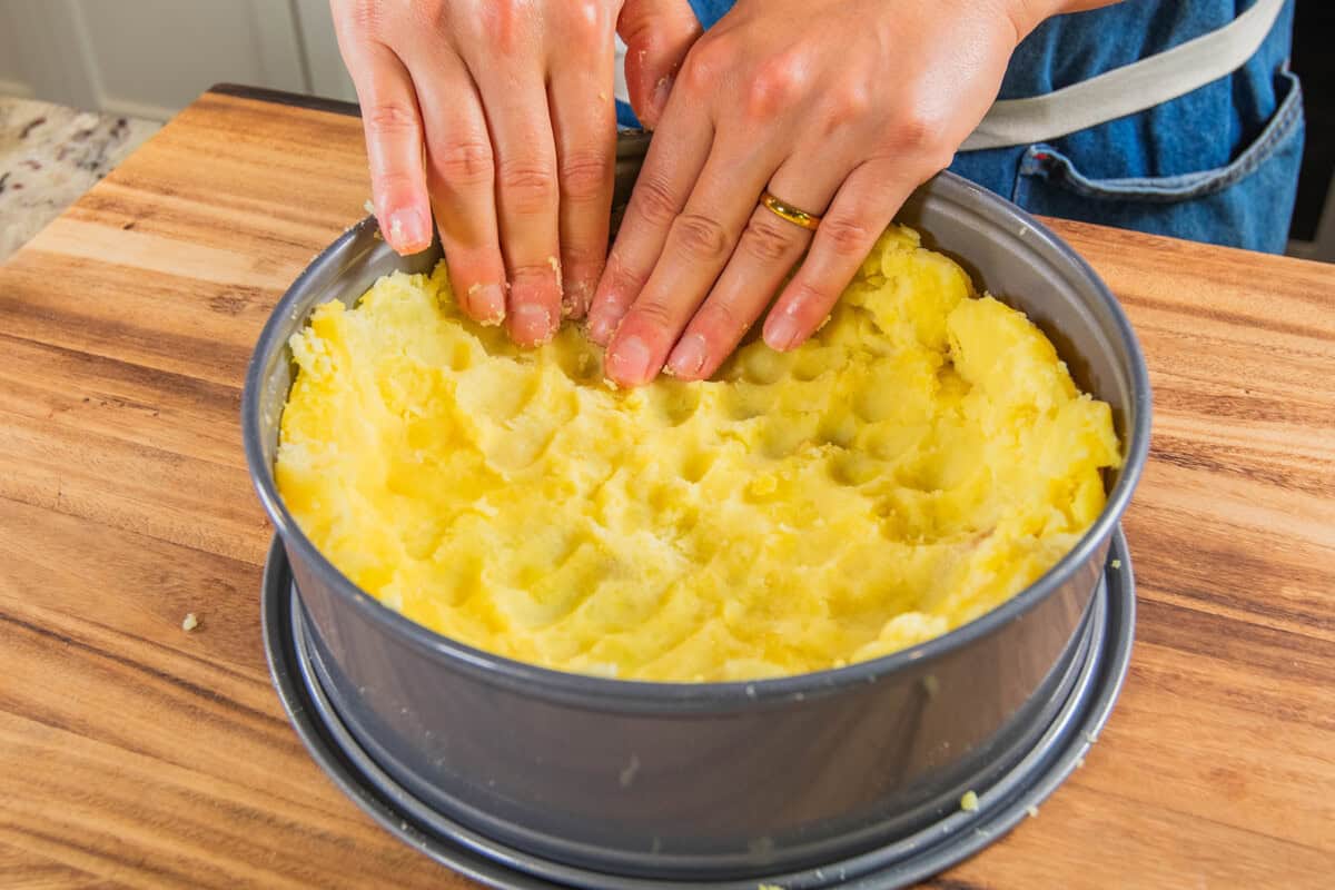pressing down potatoes in springform pan