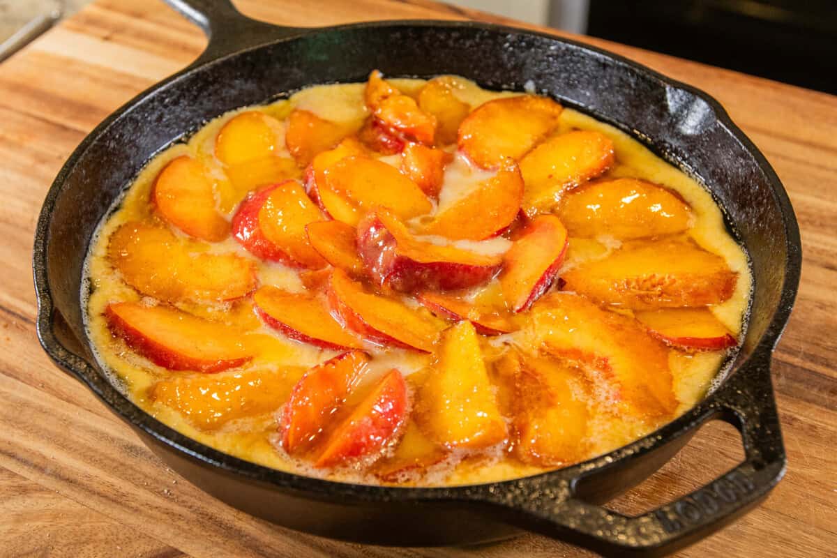 skillet with peaches and batter before baking