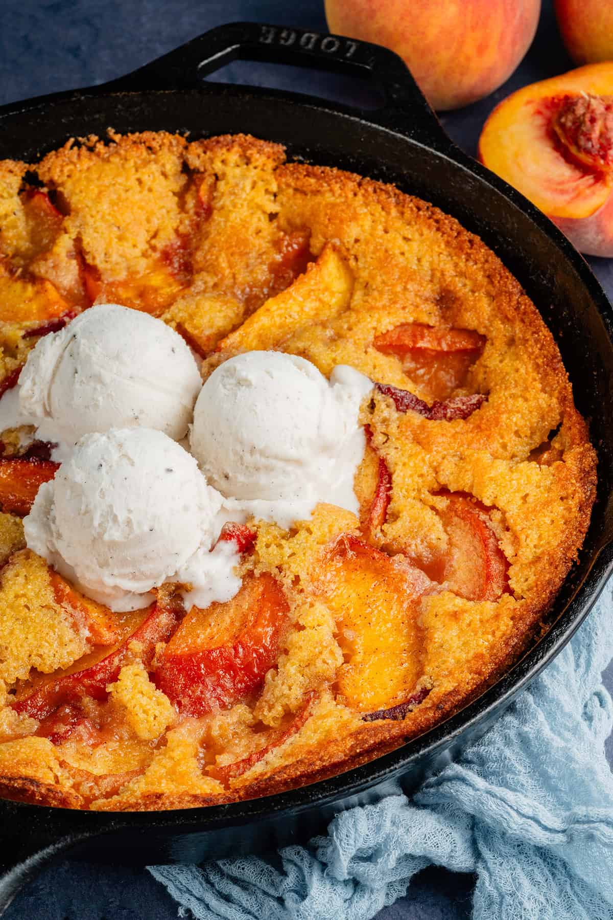 vegan peach cornbread cobbler in a skillet with ice cream on top