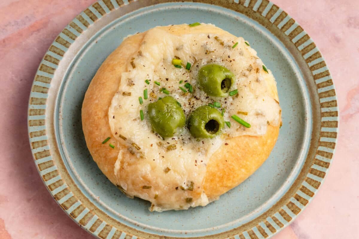 horizontal photo of Olive Chive Cream Cheese Roll on blue plate on pink table
