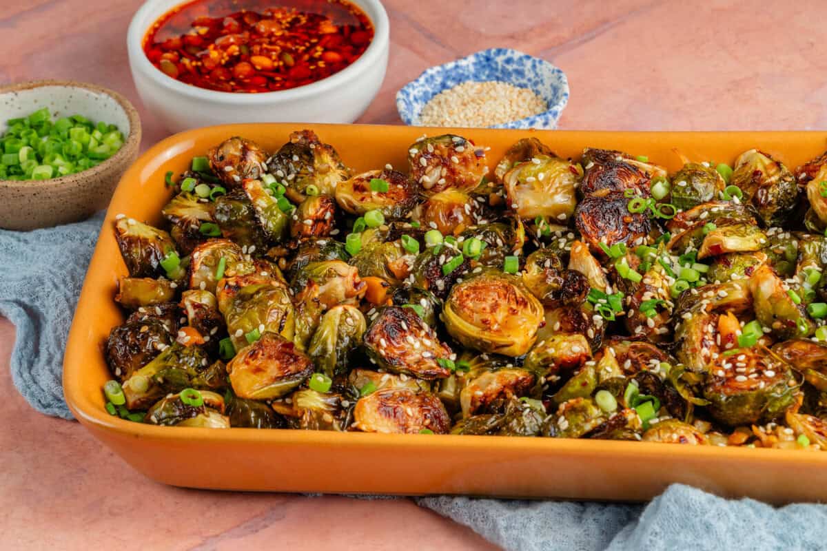 maple chili crisp brussels sprouts in yellow platter on top of blue towel