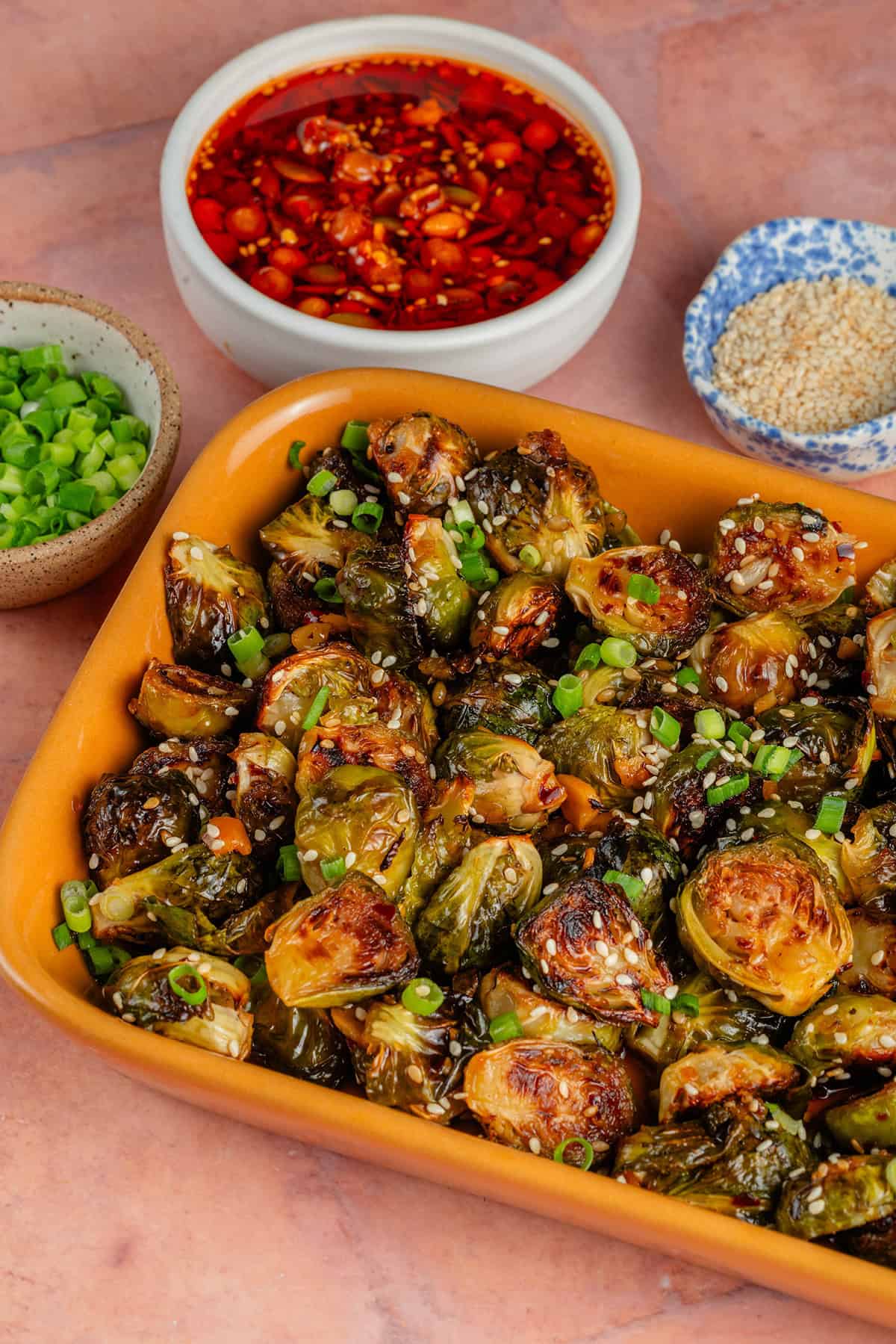 overhead of maple chili crisp brussels sprouts in yellow platter