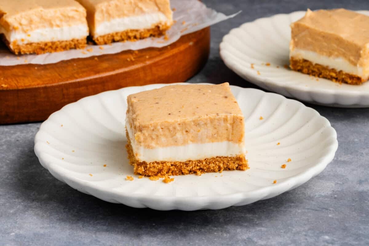 horizontal photo of a Pumpkin Cheesecake Bar on a white scalloped plate