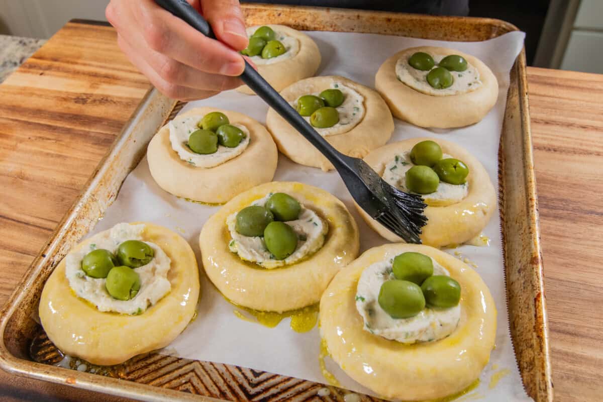 brushing Olive Chive Cream Cheese Rolls before baking