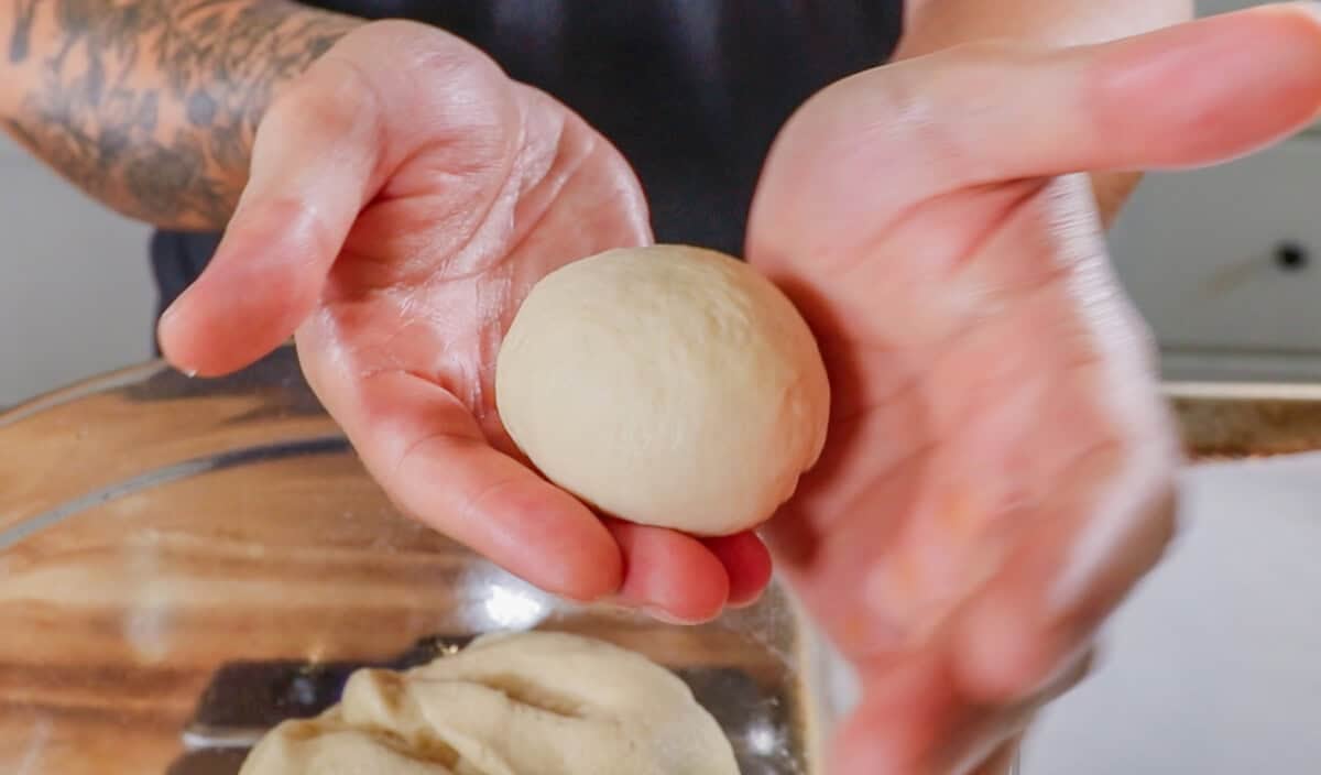 hands rolling dough into balls for Olive Chive Cream Cheese Rolls