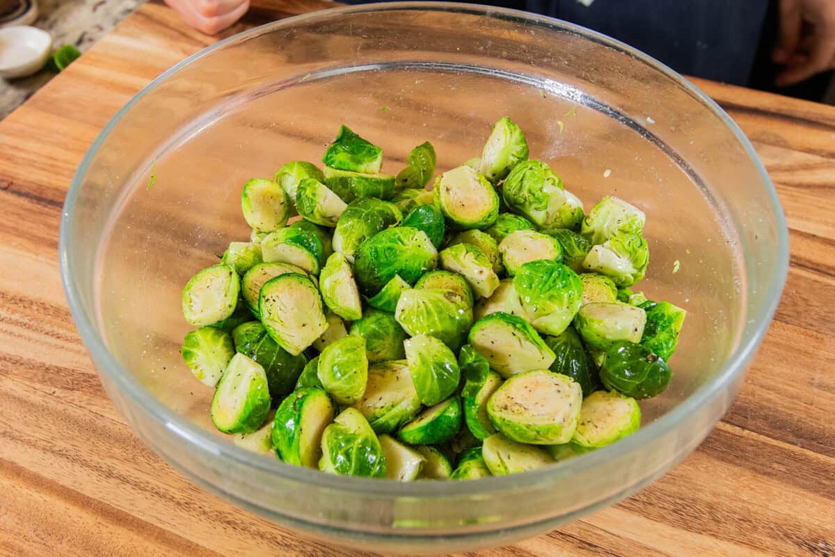 bowl of cut brussels sprouts seasoned with oil salt and pepper
