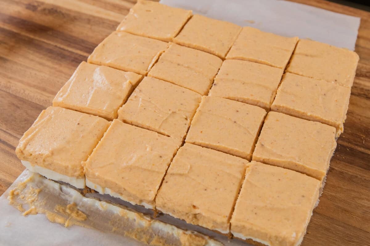 sliced pumpkin cheesecake bars on wooden board