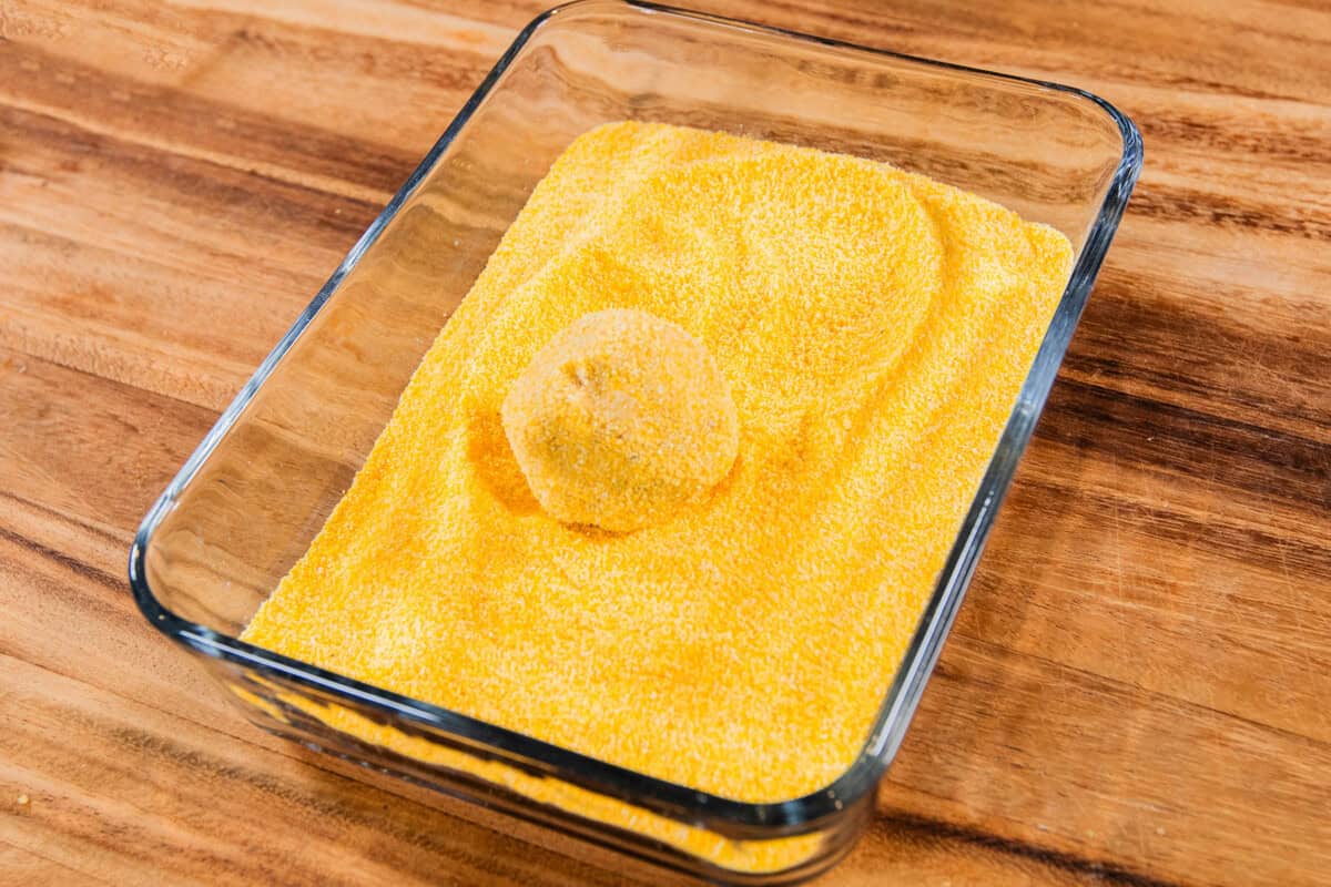rolling cornbread cookie dough balls in cornmeal