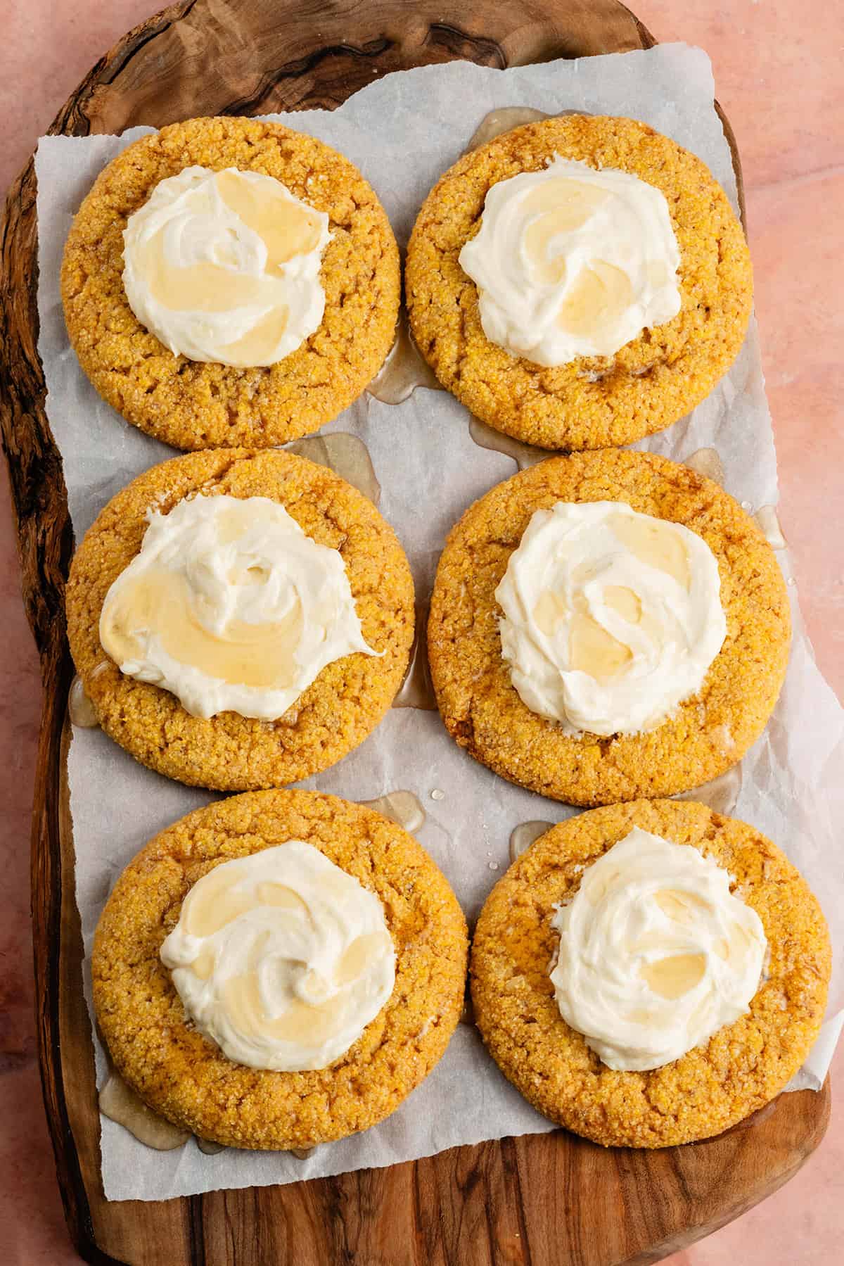 overhead of vegan cornbread cookies with agave buttercream on a wooden platter lined with parchment paper