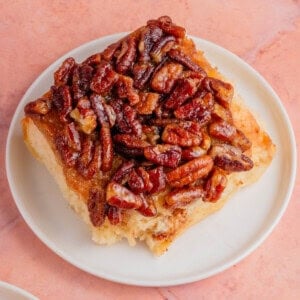maple pecan sticky buns on a white plate with a pink background