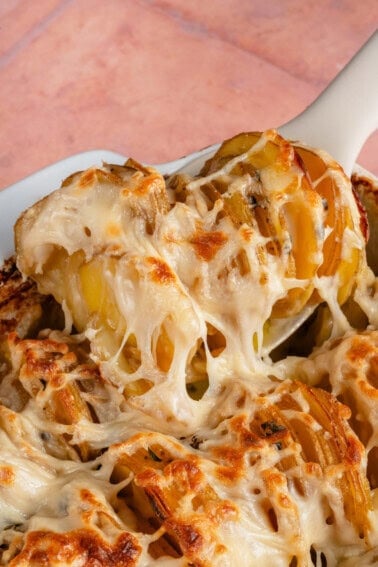 scooping Vegan Dauphinoise Potatoes from the baking dish